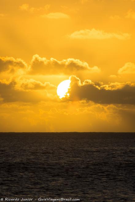Imagem de um por do sol com o céu alaranjado em Noronha.